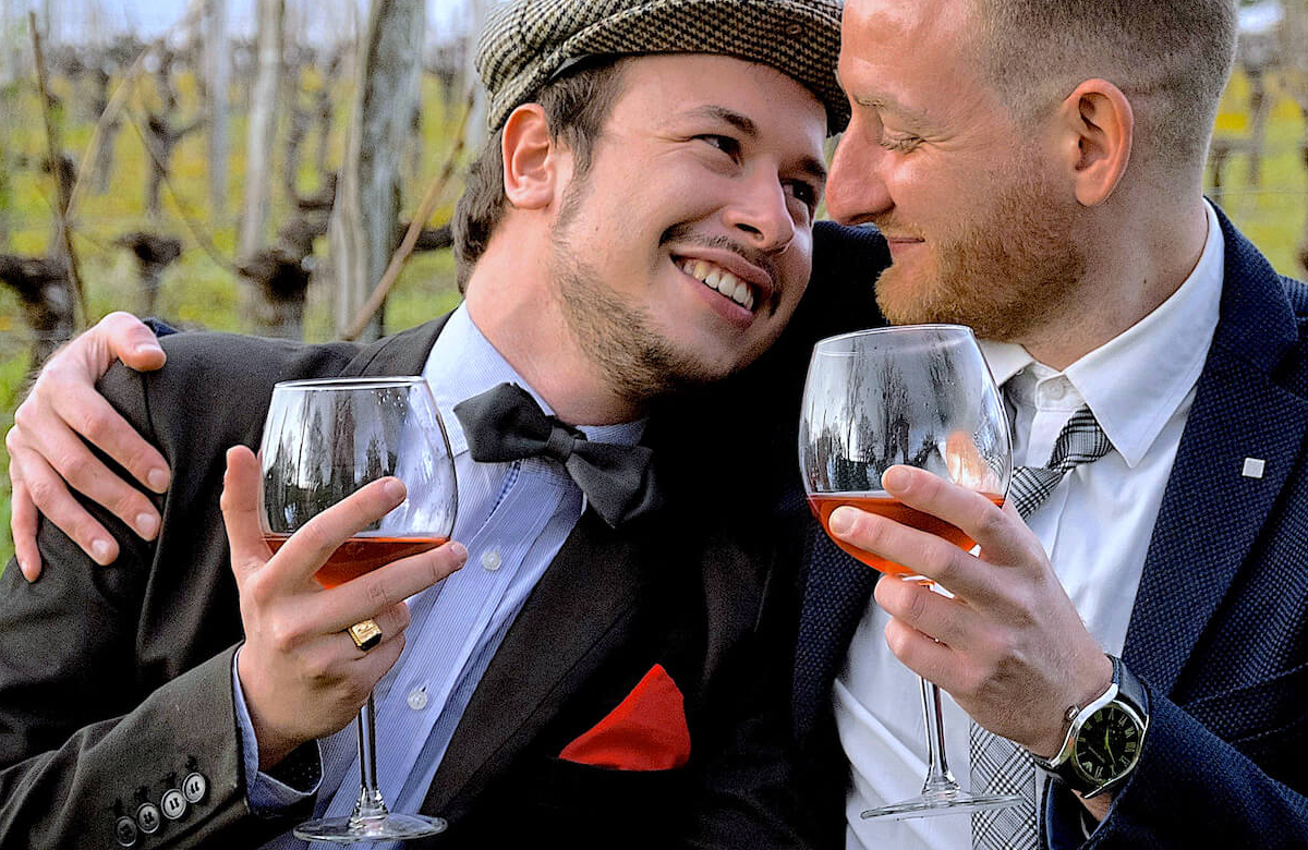 Gay couple enjoying a glass of wine together after their Jewish wedding, led by a rabbi in Europe.